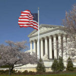 Supreme Court Rules Unanimously for Police U.S. Supreme Court building with an American flag and cherry blossom trees