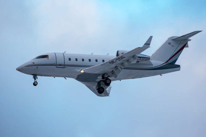 A private jet approaching for landing against a cloudy sky