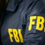 FBI STORMS Election Office — Ballots SEIZED! FBI agent in navy blue jacket.