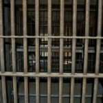 Prison Gang War Leaves Three Dead Empty, rusty barred jail cell with metal bunks.