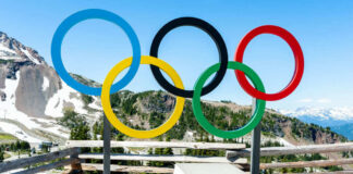 Olympic rings and podium with mountain backdrop.