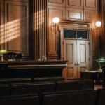 Hollywood Horror: Murder Case Back In Court Interior of a courtroom with wooden paneling and green desk lamp