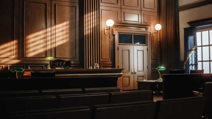 Interior of a courtroom with wooden paneling and green desk lamp