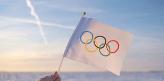 Hand holding Olympic flag in snowy landscape