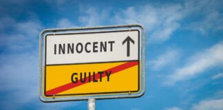 A road sign displaying 'INNOCENT' with an arrow pointing up and 'GUILTY' crossed out