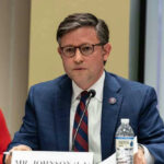 Speaker Johnson’s Nightmare: One More Missing Vote? Mike Johnson in a suit speaks into a microphone.