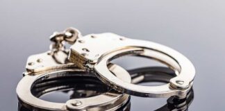 Close-up of metallic handcuffs on a reflective surface