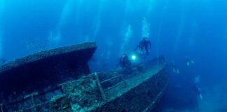 Divers exploring a sunken shipwreck underwater