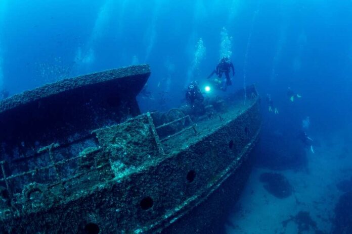 Divers exploring a sunken shipwreck underwater