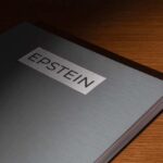 Bombshell ARREST Follows Epstein Files Release Close-up of a metallic binder labeled 'EPSTEIN'