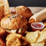 A variety of fast food items including burgers, onion rings, and chips