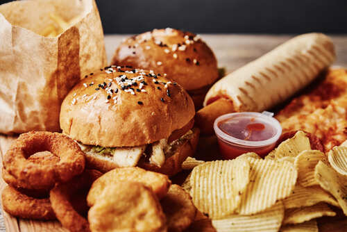 A variety of fast food items including burgers, onion rings, and chips