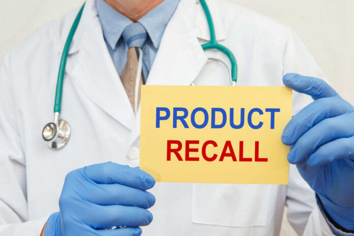 Doctor holding a product recall sign in gloves