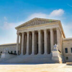 U.S. Supreme Court building exterior under blue sky.