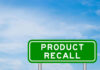 Green sign with product recall text and sky background