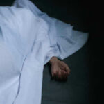 Shocking End: Missing Dad Found Dead Hand emerging from under white sheet on dark surface.