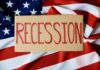 A cardboard sign reading 'RECESSION' placed on an American flag background