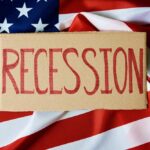 A cardboard sign reading 'RECESSION' placed on an American flag background