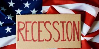 A cardboard sign reading 'RECESSION' placed on an American flag background