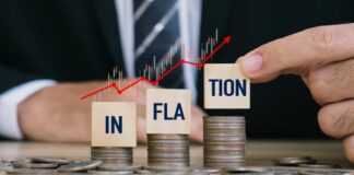 Blocks spelling 'INFLATION' placed on stacks of coins with a rising graph in the background