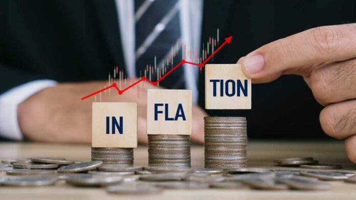 Blocks spelling 'INFLATION' placed on stacks of coins with a rising graph in the background