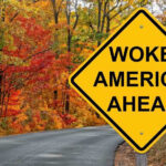 Hegseth Crushes Woke Scouting Yellow road sign: Woke America Ahead in autumn forest.