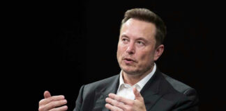 Elon Musk speaking and gesturing with hands in discussion.