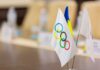 Close-up of Olympic and Ukrainian flags on a conference table