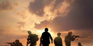 Silhouetted soldiers against a dramatic sunset sky.