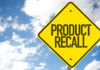 Yellow product recall sign against cloudy sky