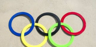 Colorful Olympic rings arranged on sandy surface
