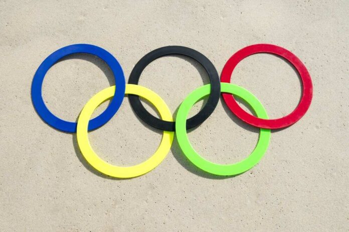 shutterstock_454228066.jpg Colorful Olympic rings arranged on sandy surface