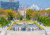 Visitors at Hiroshima Peace Memorial Park with cherry blossoms and memorial structures