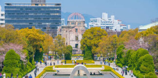 Visitors at Hiroshima Peace Memorial Park with cherry blossoms and memorial structures