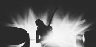 Silhouetted guitarist performing on stage with dramatic lighting.