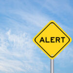 Trump Posts AI Image As JESUS — Backlash EXPLODES Yellow alert sign against a blue sky