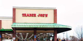 Exterior view of a Trader Joe's grocery store with customers waiting outside