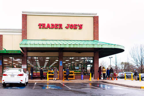 Exterior view of a Trader Joe's grocery store with customers waiting outside