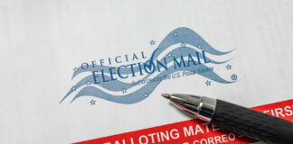 Vote-by-mail envelope with pen on top.