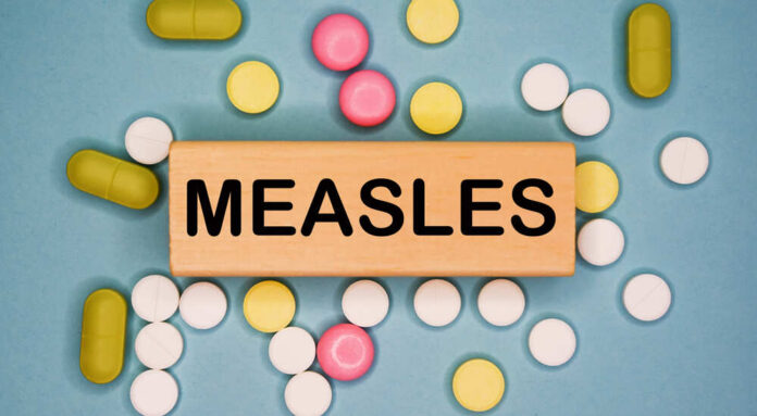 Wooden block with the word 'MEASLES' surrounded by various pills