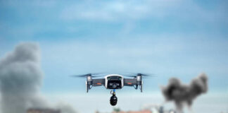 Drone flying over urban area with smoke plumes.