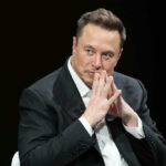 Elon Musk in suit thinking.