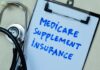 Clipboard with handwritten text about Medicare supplement insurance next to a stethoscope
