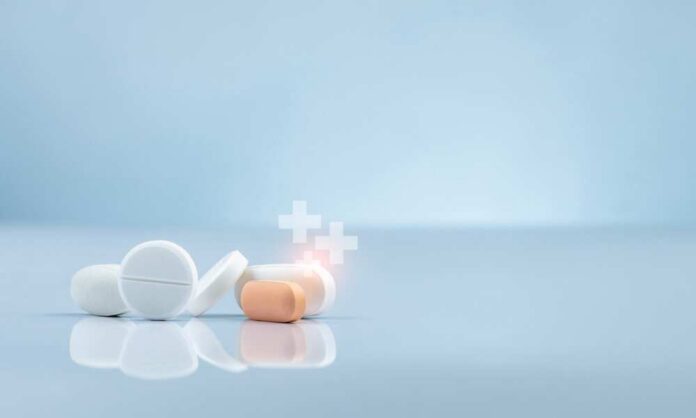 Assorted pills on a reflective surface against a light background