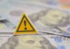 A warning sign placed on top of U.S. dollar bills