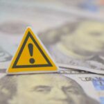 A warning sign placed on top of U.S. dollar bills