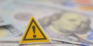 A warning sign placed on top of U.S. dollar bills