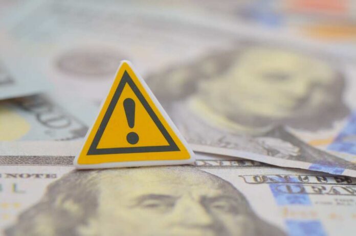 A warning sign placed on top of U.S. dollar bills