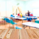 Blurred classroom with students and a wooden foreground.