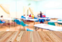 Blurred classroom with students and a wooden foreground.